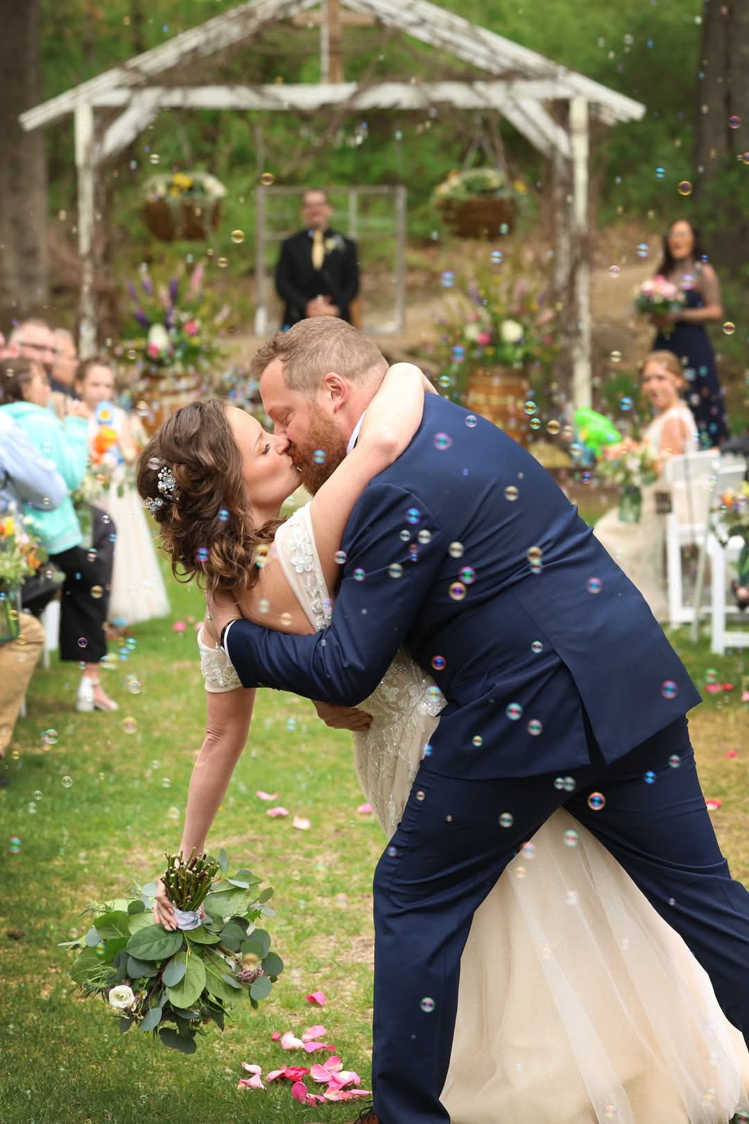 Bride and groom share a romantic kiss surrounded by bubbles after their outdoor wedding ceremony at Caribou Bay Retreat in Coloma, Wisconsin.