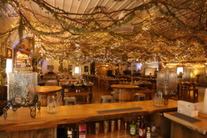 Rustic hydration station inside Caribou Bay’s event barn, surrounded by twinkling lights and wooden furniture.
