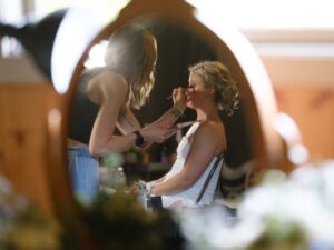 Bride having makeup applied in front of a mirror before her wedding ceremony at Caribou Bay Retreat