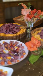 Charcuterie spread with cheese, meats, and fresh flowers on a rustic grazing table at Caribou Bay Retreat in Central Wisconsin