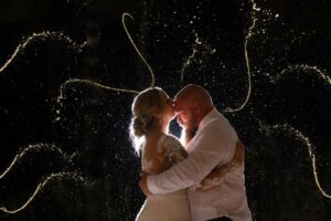 Bride and groom embrace under sparkling lights at night during their wedding at Caribou Bay Retreat.
