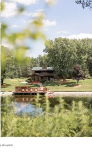 Central Wisconsin wedding venue near Oshkosh at Caribou Bay Retreat – lakeside lodge and deck overlooking the private waterfront surrounded by trees and summer greenery.