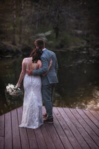vvCentral Wisconsin wedding venue near Appleton at Caribou Bay Retreat – bride and groom embracing on the lakeside deck at sunset, overlooking the peaceful water.