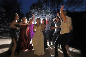 Central Wisconsin wedding venue near Wisconsin Dells at Caribou Bay Retreat – bride celebrating at night surrounded by guests, with bubbles and joyful motion lighting up the dance party.