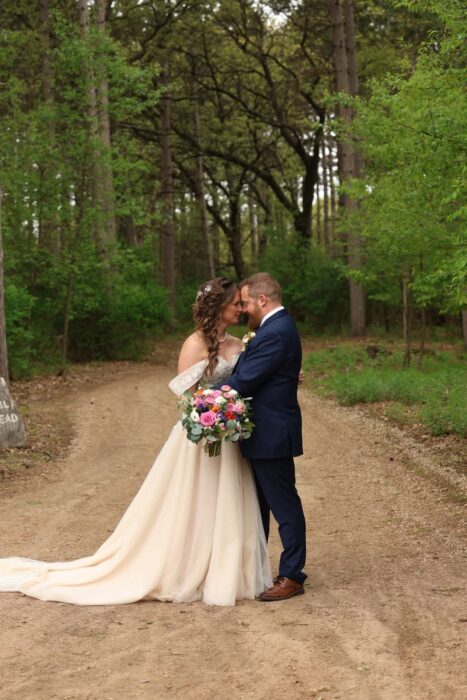 Central Wisconsin wedding venue near Wisconsin Dells at Caribou Bay Retreat – bride and groom embracing on a wooded forest path surrounded by lush green trees