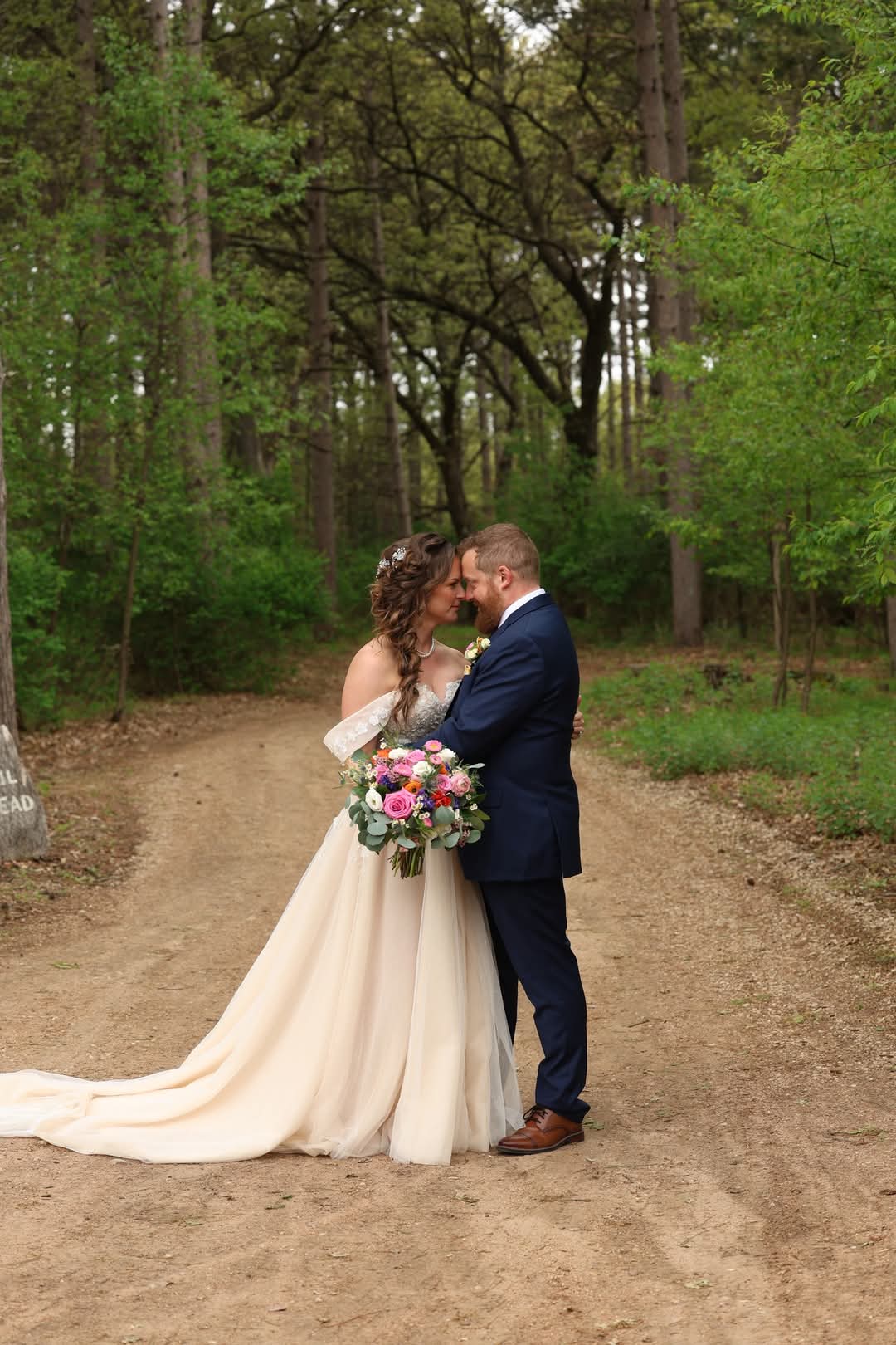 Central Wisconsin wedding venue near Wisconsin Dells at Caribou Bay Retreat – bride and groom embracing on a wooded forest path surrounded by lush green trees