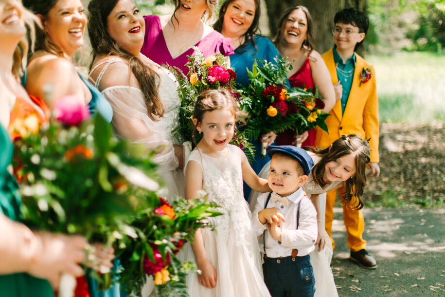 Central Wisconsin wedding venue near Wisconsin Dells at Caribou Bay Retreat – joyful bride surrounded by bridesmaids and children in colorful attire sharing a candid outdoor moment during a wedding celebration.