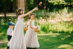 Central Wisconsin wedding venue near Appleton at Caribou Bay Retreat – flower girls and ring bearer tossing petals along the outdoor chapel aisle surrounded by soft woodland sunlight.
