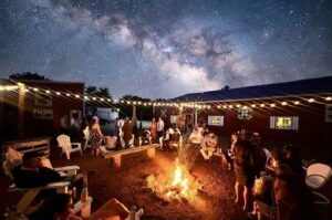 Central Wisconsin wedding venue near Portage at Caribou Bay Retreat – guests gathered around a glowing fire pit under string lights and a star-filled night sky during a wedding weekend celebration.