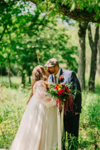 Central Wisconsin wedding venue near Wisconsin Dells at Caribou Bay Retreat – bride and groom sharing a quiet kiss beneath a leafy tree during a romantic woodland moment.