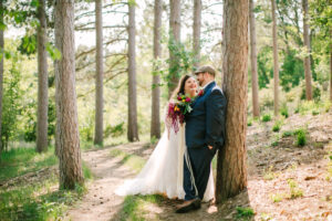 Central Wisconsin wedding venue near Stevens Point at Caribou Bay Retreat – bride and groom sharing a romantic moment along a sunlit pine woodland trail.