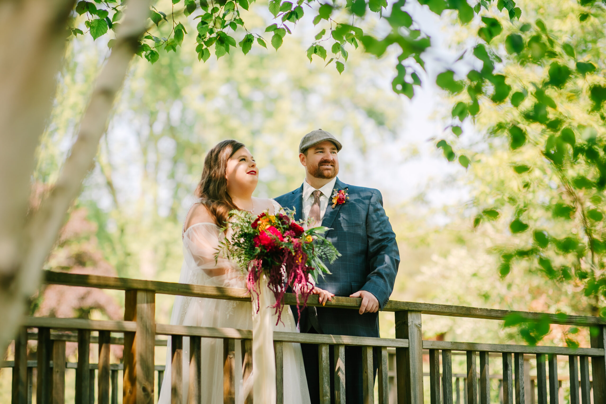 Central Wisconsin wedding venue near Wisconsin Dells at Caribou Bay Retreat – bride and groom standing on a wooden bridge surrounded by lush greenery holding a vibrant bouquet