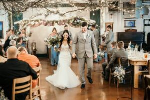 Central Wisconsin wedding venue near Stevens Point at Caribou Bay Retreat – bride and groom walking down the aisle indoors under twinkle lights with guests celebrating
