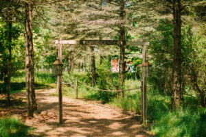 Central Wisconsin wedding venue near Portage at Caribou Bay Retreat – wooded path leading to the event center with rustic signage and lantern accents